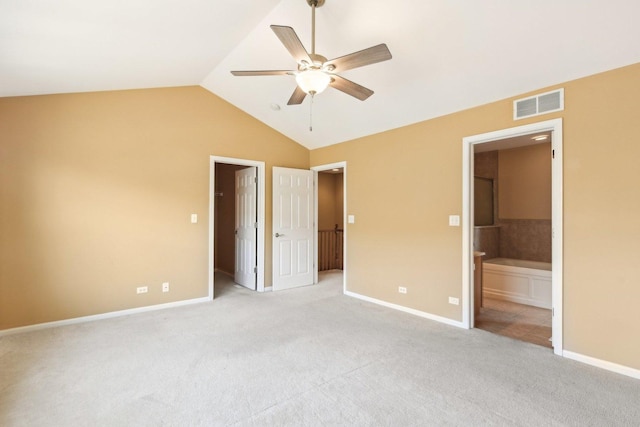 unfurnished bedroom featuring ceiling fan, light carpet, vaulted ceiling, and ensuite bath