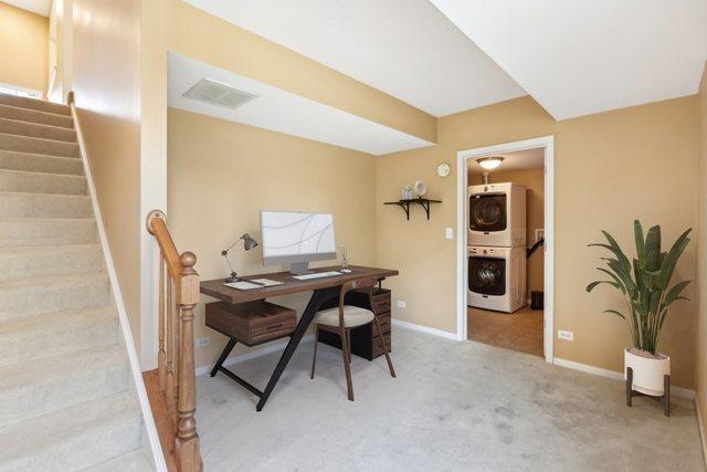 carpeted home office with stacked washer and dryer