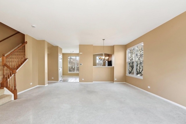 unfurnished living room with light carpet and a notable chandelier