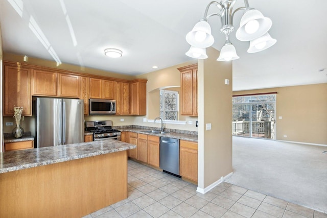 kitchen with sink, appliances with stainless steel finishes, decorative light fixtures, a chandelier, and light colored carpet