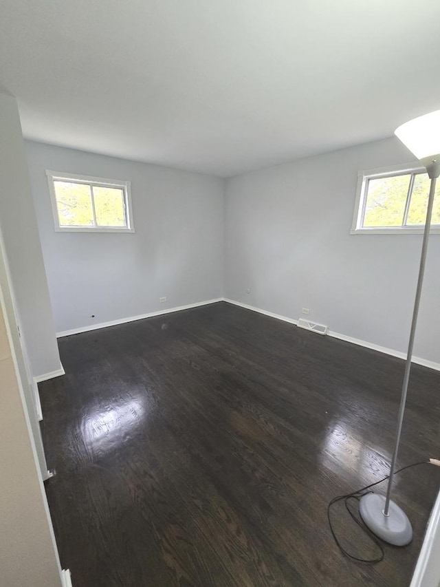 empty room featuring plenty of natural light and dark hardwood / wood-style floors