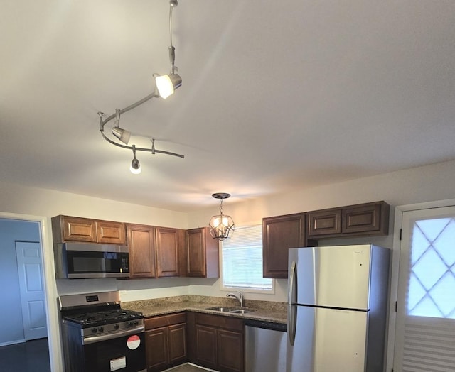 kitchen featuring appliances with stainless steel finishes, decorative light fixtures, a notable chandelier, and sink