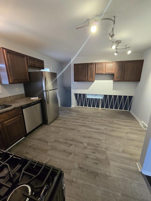 kitchen with hardwood / wood-style floors, dark brown cabinetry, stainless steel appliances, and sink