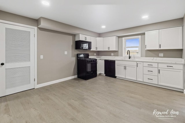 kitchen featuring black appliances, white cabinets, sink, light wood-type flooring, and light stone counters