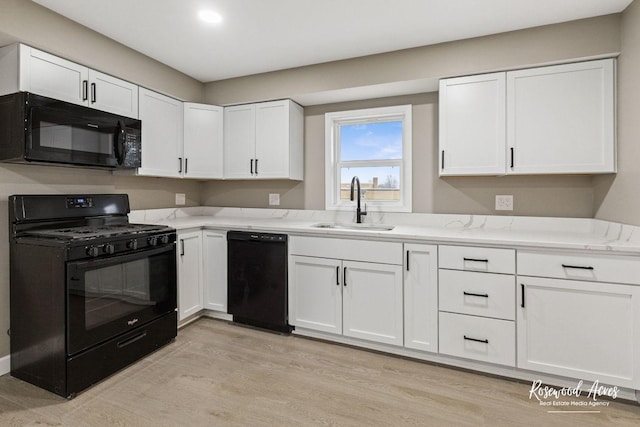 kitchen featuring sink, white cabinets, black appliances, and light hardwood / wood-style floors