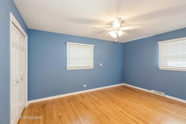 unfurnished bedroom with multiple windows, a closet, ceiling fan, and light hardwood / wood-style floors