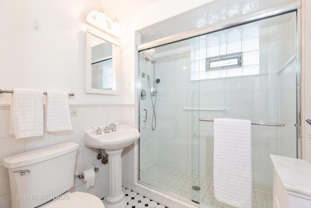 bathroom with toilet, a shower with door, and tile walls