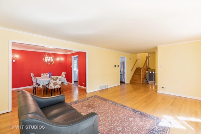 living room with hardwood / wood-style flooring, a notable chandelier, and crown molding