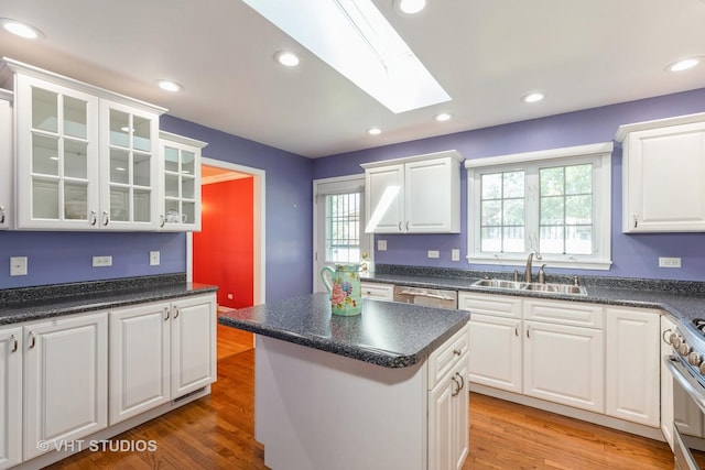 kitchen featuring a skylight, hardwood / wood-style floors, white cabinets, and a kitchen island