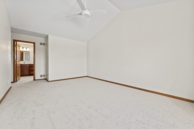 interior space featuring light colored carpet, ceiling fan, connected bathroom, and vaulted ceiling