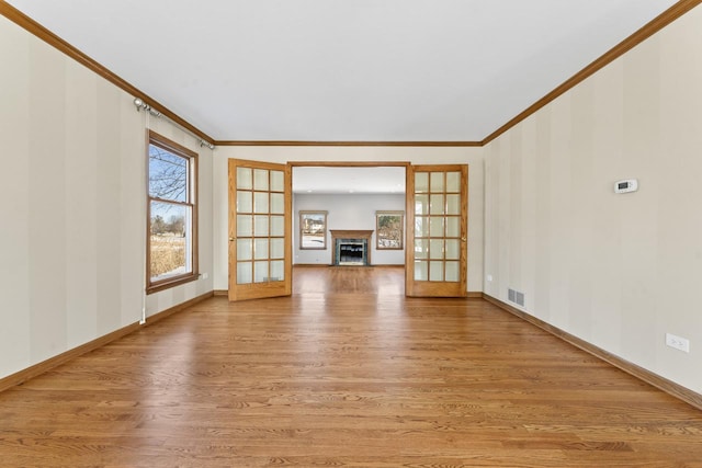 unfurnished living room with french doors, crown molding, and light wood-type flooring