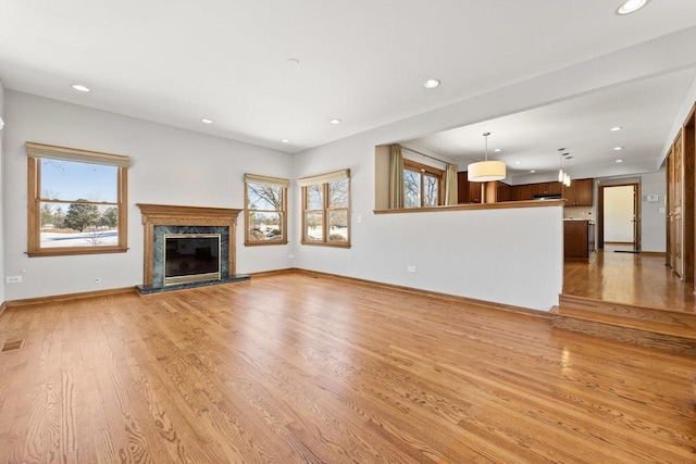 unfurnished living room featuring a high end fireplace and light hardwood / wood-style flooring