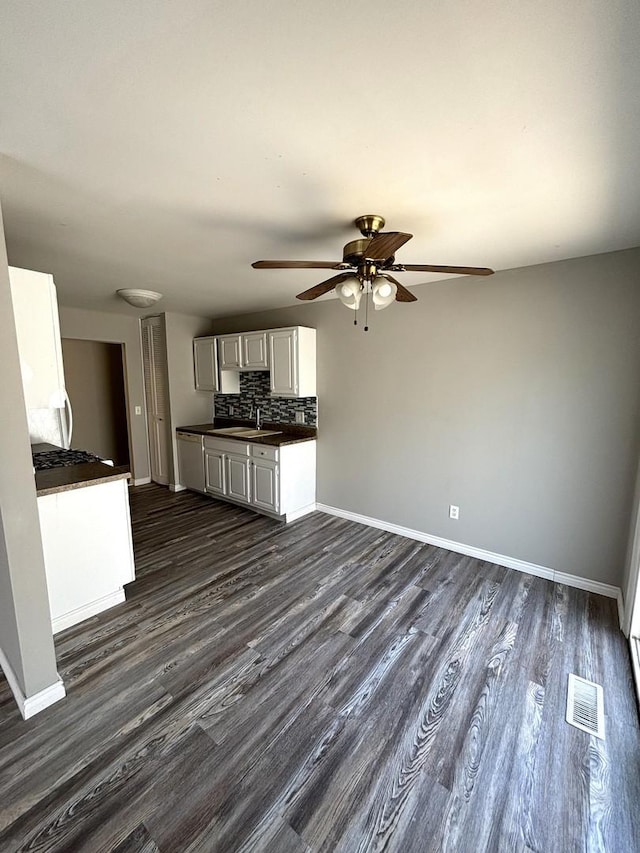 unfurnished living room featuring dark hardwood / wood-style floors, ceiling fan, and sink