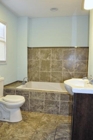 bathroom with tiled tub, toilet, and vanity