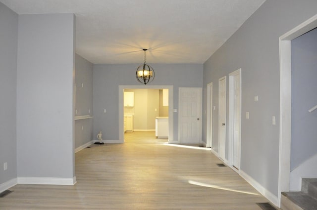 empty room featuring light hardwood / wood-style floors and a notable chandelier