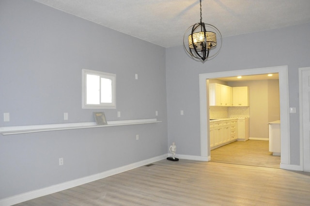 spare room featuring light hardwood / wood-style floors and a notable chandelier