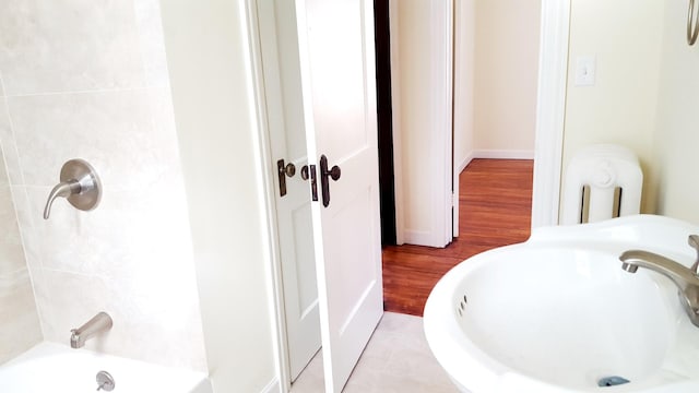 bathroom with hardwood / wood-style flooring, sink, and bathing tub / shower combination