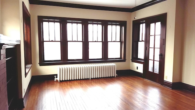 interior space featuring hardwood / wood-style flooring, radiator heating unit, and crown molding