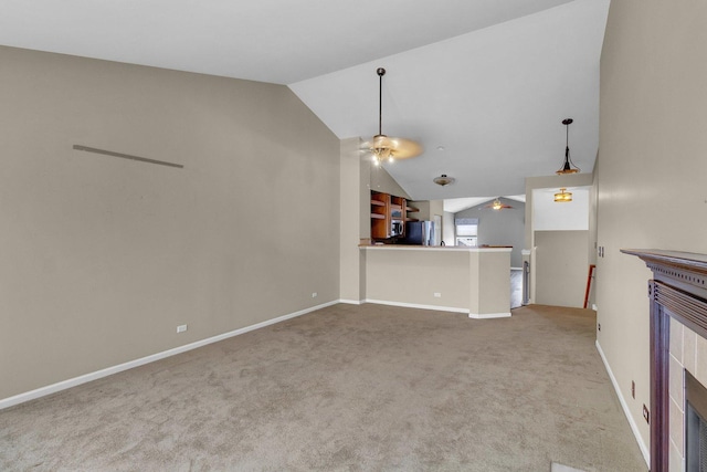 unfurnished living room with a tile fireplace, light colored carpet, vaulted ceiling, and ceiling fan