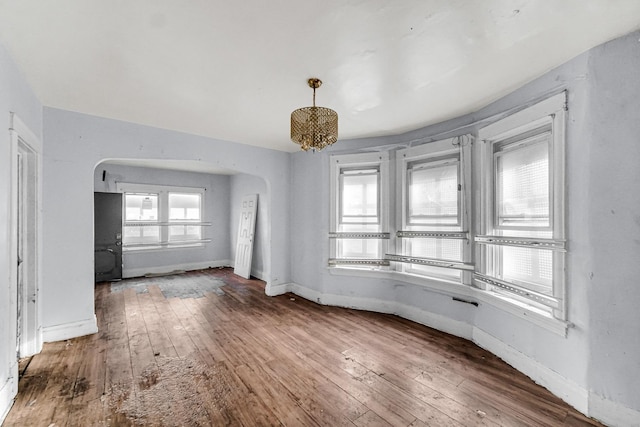 empty room featuring a chandelier and hardwood / wood-style flooring