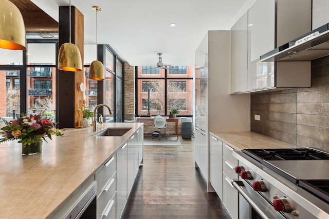 kitchen featuring sink, high end stainless steel range, wall chimney exhaust hood, tasteful backsplash, and white cabinetry