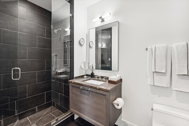 bathroom featuring a shower with door, vanity, and toilet