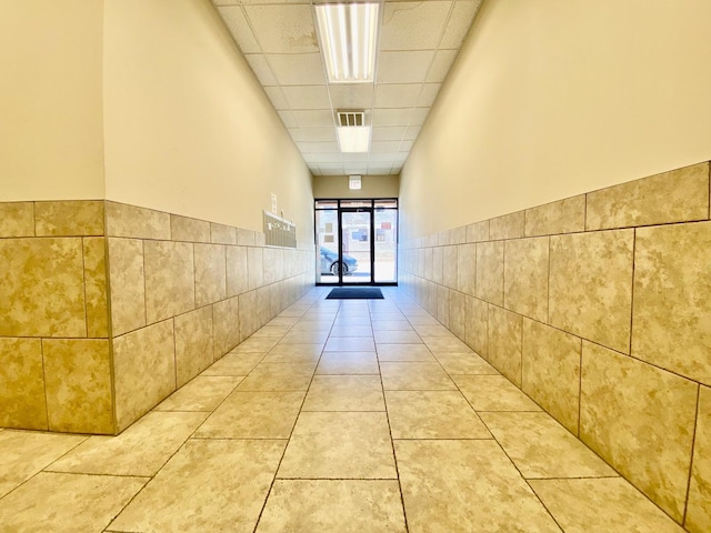 corridor featuring a drop ceiling and light tile patterned floors