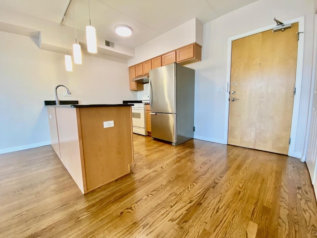 kitchen featuring kitchen peninsula, light hardwood / wood-style flooring, stainless steel fridge, decorative light fixtures, and white range with gas stovetop