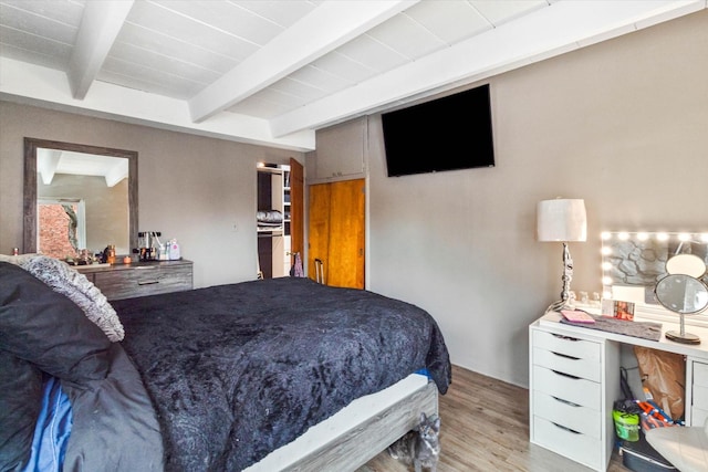 bedroom featuring beamed ceiling and light hardwood / wood-style floors