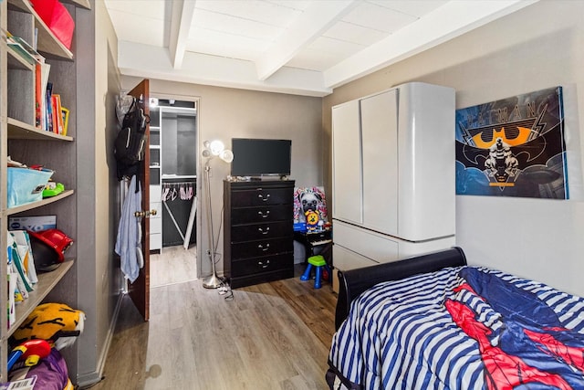 bedroom with beamed ceiling, light hardwood / wood-style flooring, and a closet