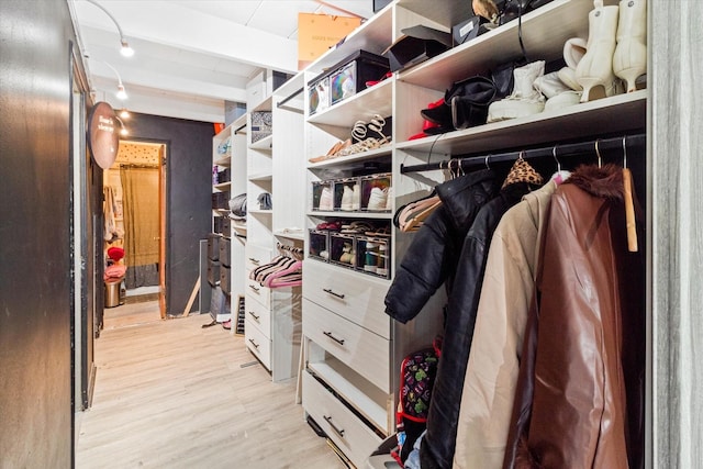 spacious closet featuring beamed ceiling and light hardwood / wood-style flooring