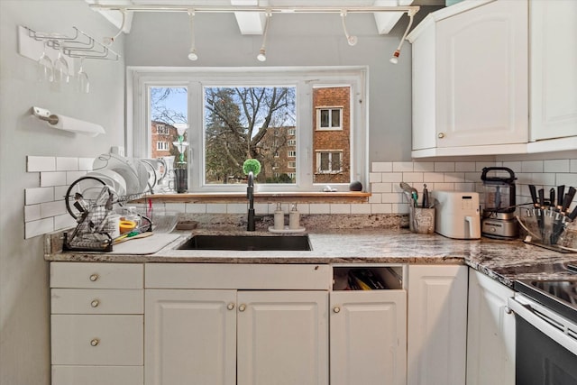 kitchen with decorative backsplash, sink, and white cabinets