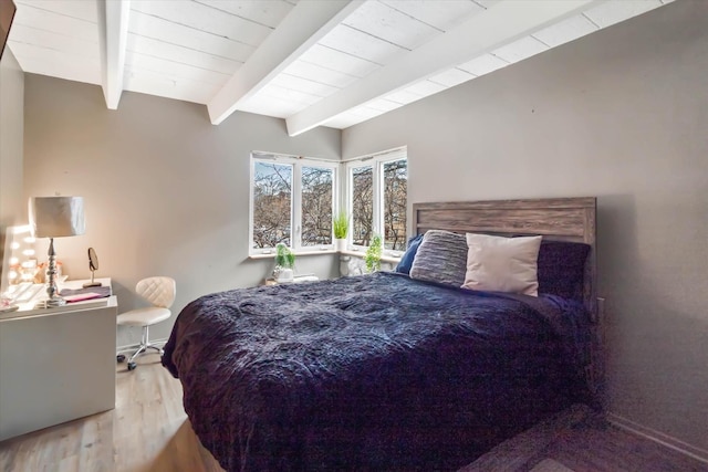 bedroom with beam ceiling and hardwood / wood-style floors