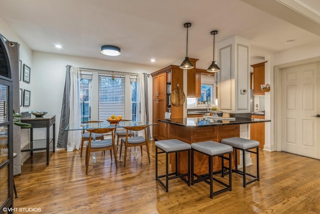 kitchen featuring dark stone counters, hardwood / wood-style floors, pendant lighting, and a kitchen breakfast bar