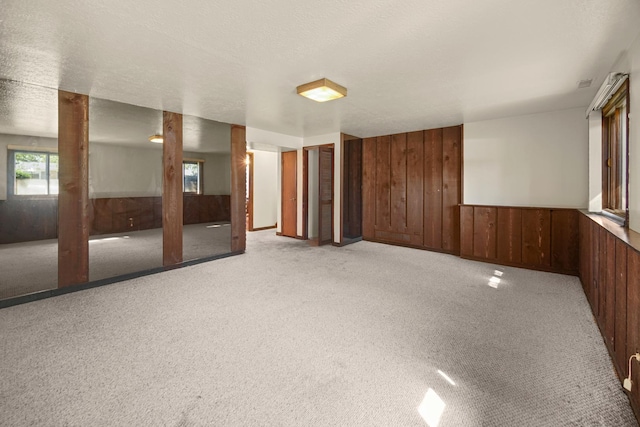 carpeted spare room featuring wood walls and a textured ceiling