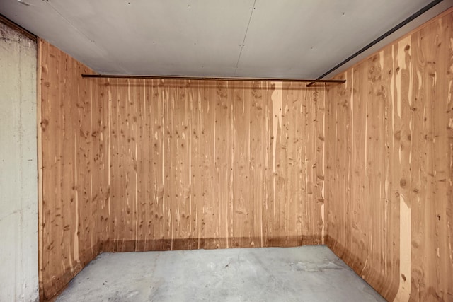 unfurnished room featuring concrete flooring and wood walls