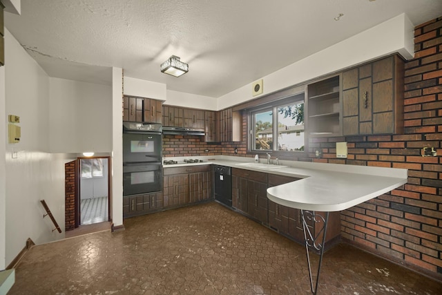 kitchen with kitchen peninsula, a kitchen bar, dark brown cabinets, double oven, and sink