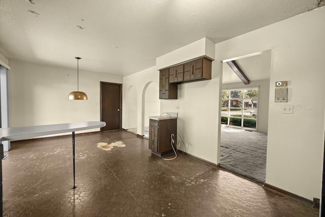 kitchen featuring beamed ceiling, dark brown cabinets, and a textured ceiling