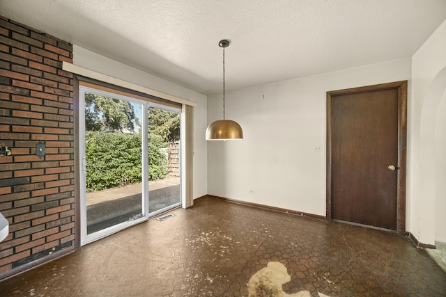 unfurnished dining area featuring a textured ceiling