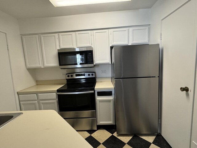 kitchen with white appliances, white cabinetry, radiator heating unit, light carpet, and kitchen peninsula