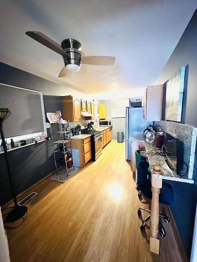 interior space featuring appliances with stainless steel finishes, light wood-type flooring, backsplash, ceiling fan, and lofted ceiling