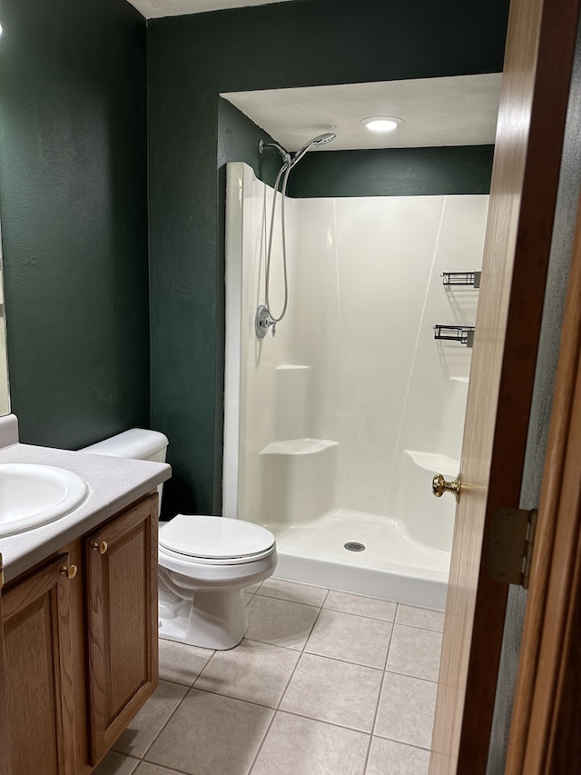 bathroom featuring tile patterned flooring, a shower, vanity, and toilet