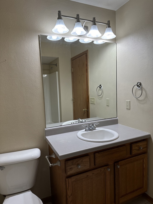 bathroom featuring vanity, toilet, and walk in shower