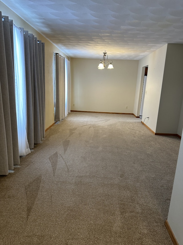 carpeted spare room with a notable chandelier