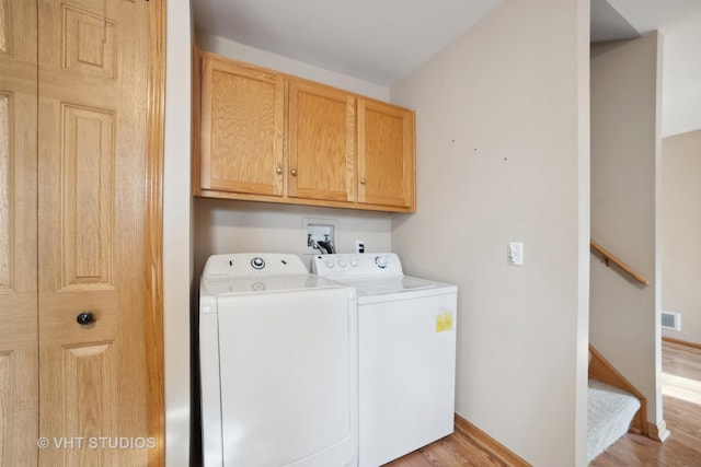 laundry room featuring washer and clothes dryer, cabinets, and light hardwood / wood-style flooring