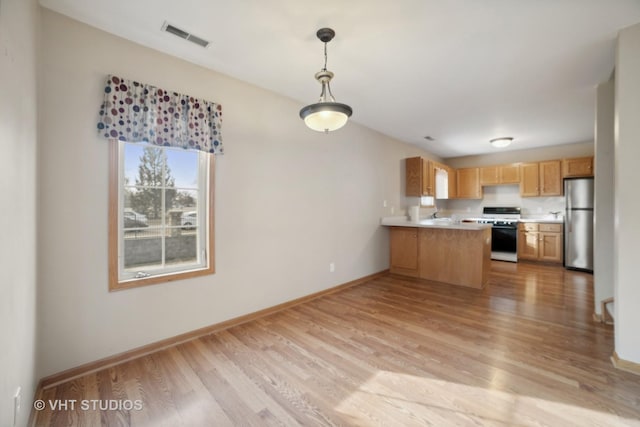 kitchen with stainless steel refrigerator, kitchen peninsula, decorative light fixtures, white stove, and light wood-type flooring