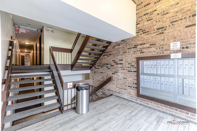 staircase featuring brick wall, mail boxes, and wood-type flooring