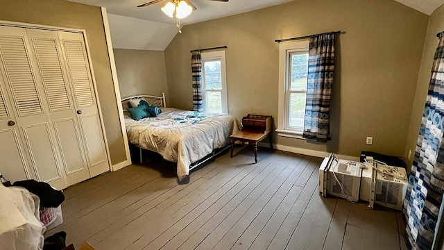 bedroom with ceiling fan, a wall mounted air conditioner, wood-type flooring, vaulted ceiling, and a closet