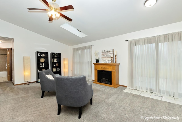 carpeted living room with vaulted ceiling with skylight and ceiling fan