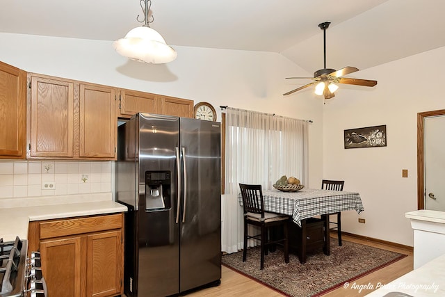 kitchen featuring stainless steel appliances, light hardwood / wood-style flooring, backsplash, lofted ceiling, and decorative light fixtures